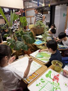 京都の絵画教室OWL美術研究所子供アトリエの授業風景観葉植物に恐竜フィギアを配置したモチーフを囲んで
