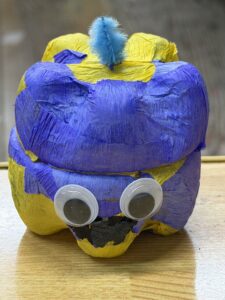 青と紫の紙を貼り、大きめの目玉シールと黄色い飾りをつけた個性的で立体的なペットボトルランタン作品