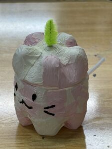 薄いピンクや白のクレープペーパーを貼り、緑のモールとネコのような可愛い顔をつけたペットボトルランタン作品